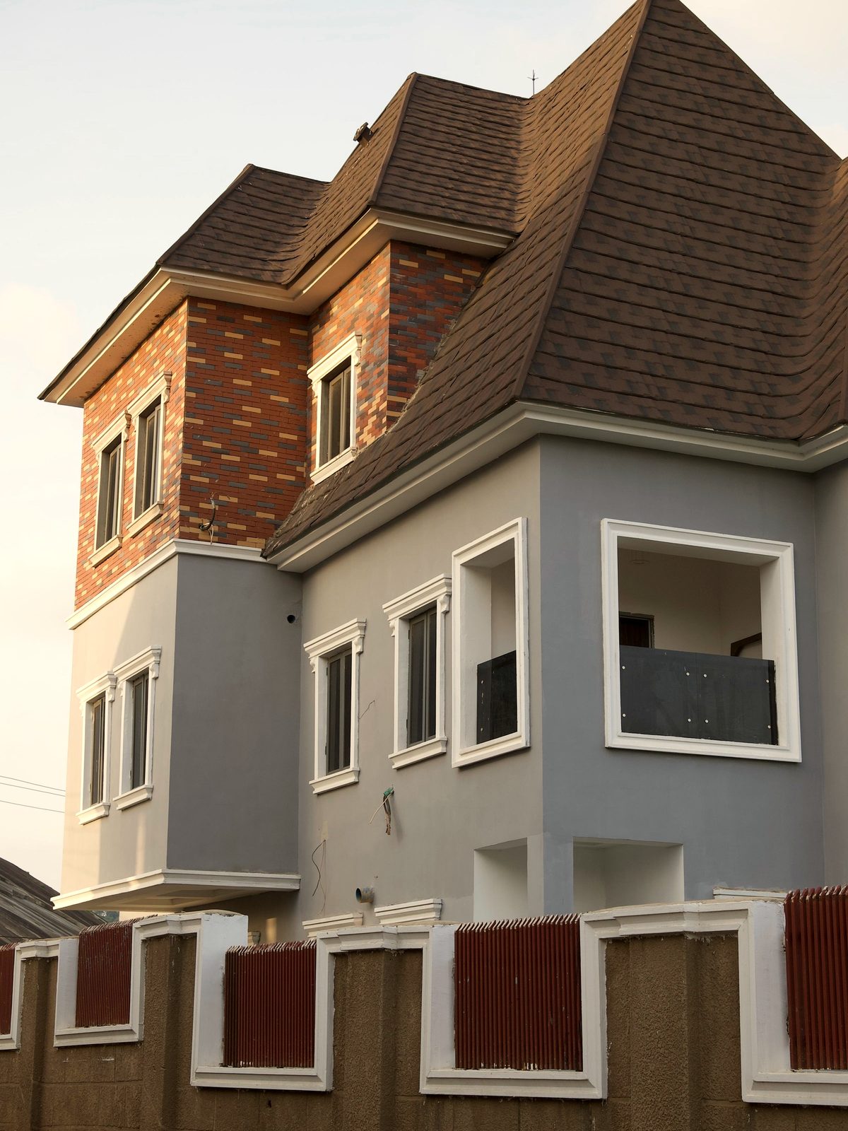 A newly built two-storey Nigerian residence, brick and rendered façade, photographed in evening light.